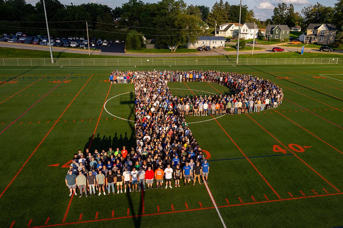 Two UW-Platteville students in orange shirts holding welcome signs on move in day