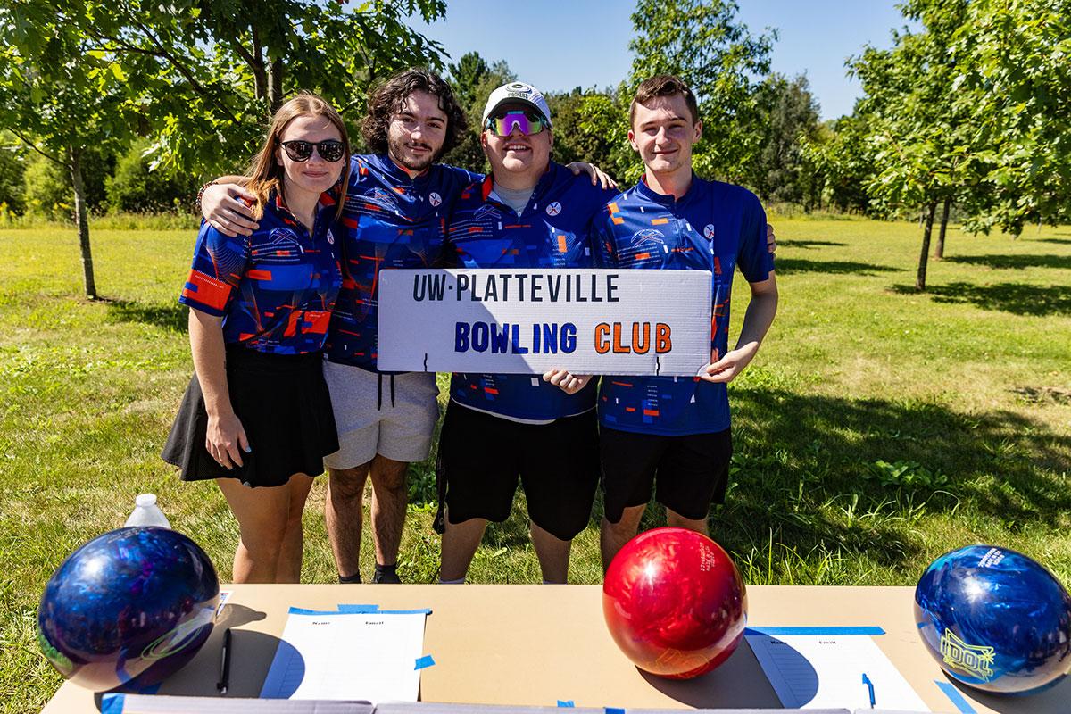Two UW-Platteville students in orange shirts holding welcome signs on move in day