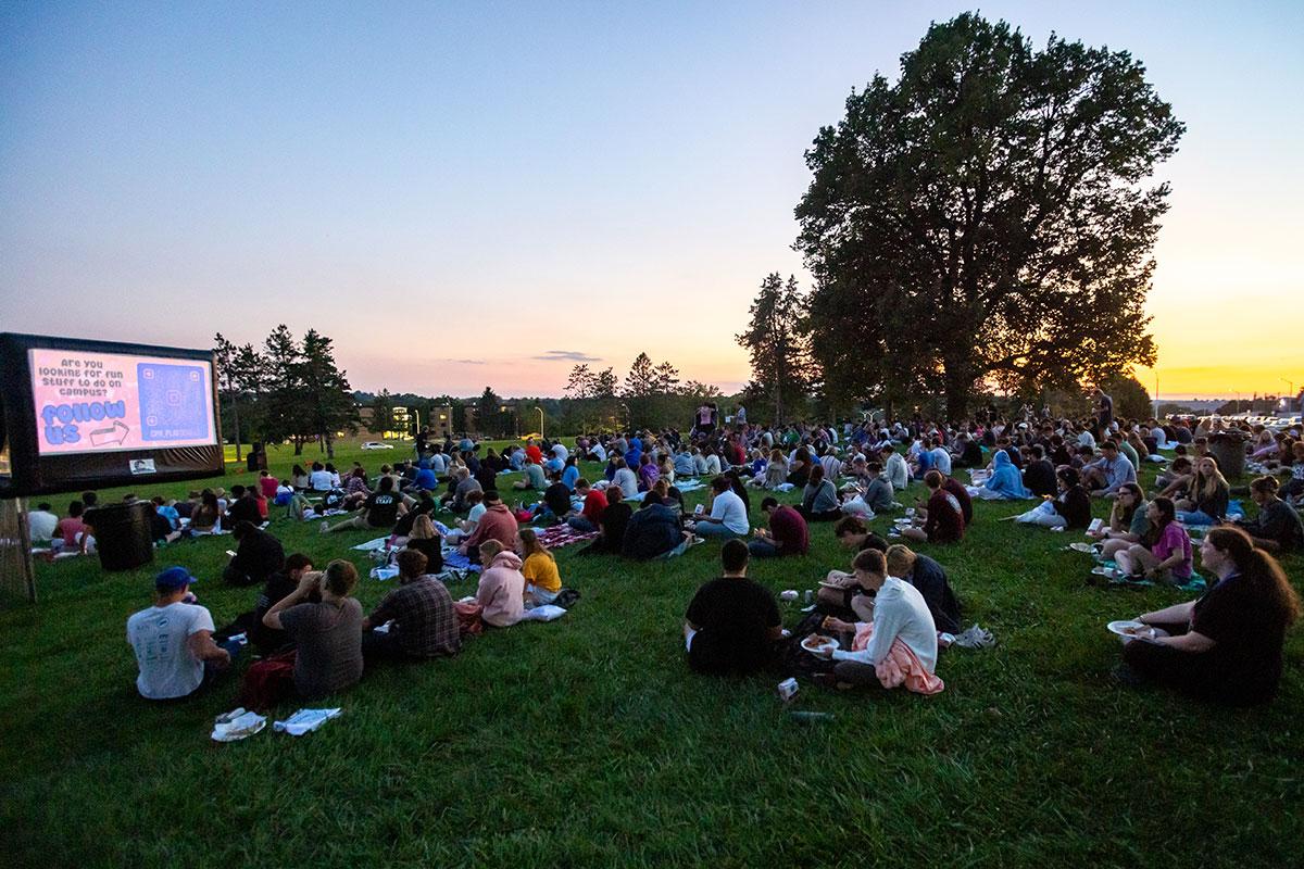 Two UW-Platteville students in orange shirts holding welcome signs on move in day