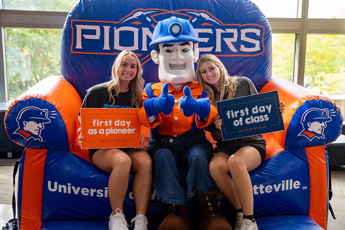 Two UW-Platteville students in orange shirts holding welcome signs on move in day