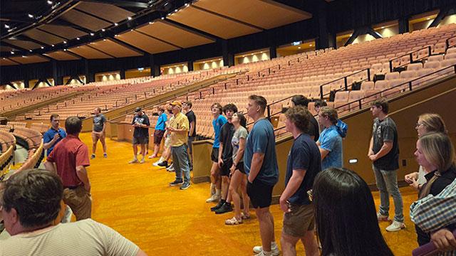 Group of students and faculty standing in an auditorium