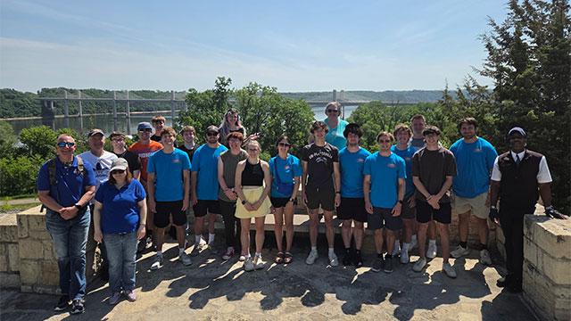 Group of students and faculty posing in front of a bridge