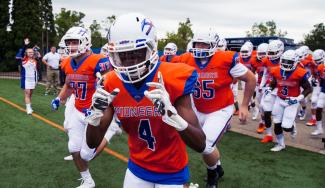 UW-Platteville Pioneers football team members in uniform running on to the playing field