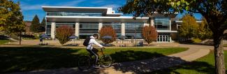 Student riding bike past Ullsvik Hall