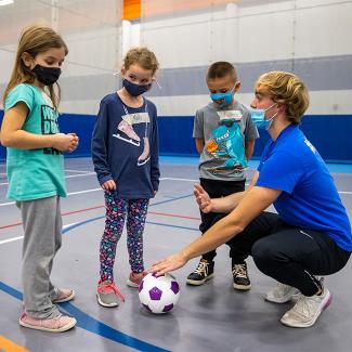Student teaching soccer to children