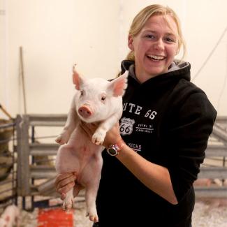 Agriculture student holding piglet