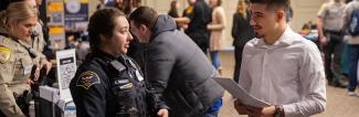A student talks with a police officer at a career fair