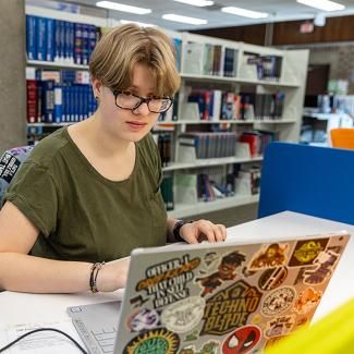 student working on laptop in library