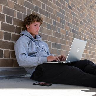 UW-Platteville student sitting outside with laptop