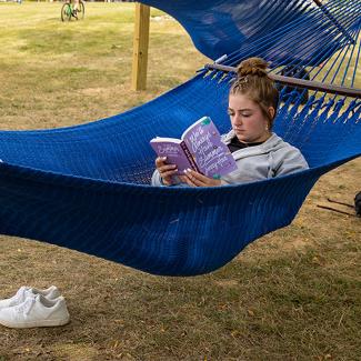 woman laying in hammock reading a book