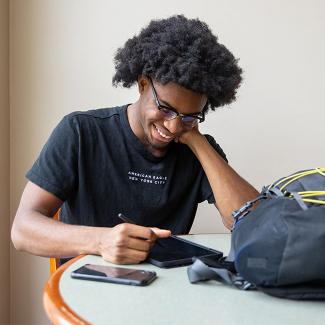 student sitting at table with electronic devices 