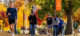 UW-Platteville students walk across campus on fall day with university banner in the background