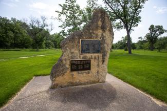 World War II Memorial plaque mounted to stone in cultivated park