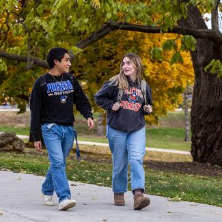 Two UW-Platteville students walking along campus path in the fall