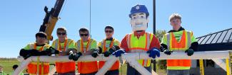 Students and Pioneer Pete wearing yellow safety vests at Construction Career Day