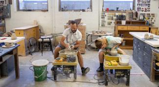 Two UW-Platteville students shape pots on pottery wheel