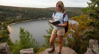 Assisting in lab research, a UW-Platteville student stands on a bluff overlooking the lake