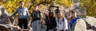 A group of students from UW-Platteville takes a photo while hiking a rocky trail during a field trip.