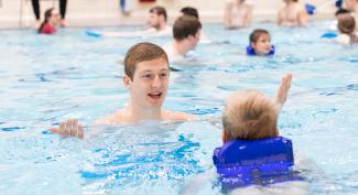 UW-Platteville student giving swimming instructions to an adolescent