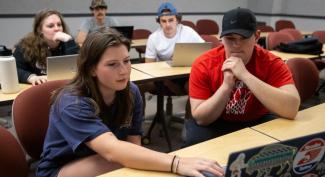 UW-Platteville business students sit with laptops while participating in a group discussion.