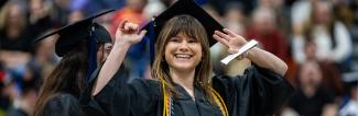 UW-Platteville student smiling with hands in the air at commencement