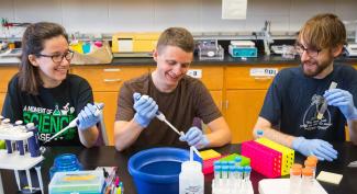 Three smiling UW-Platteville students use pipettes in lab