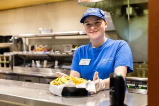 UW-Platteville dining staff member in blue shirt with basket of food