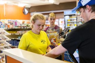 UW-Platteville student in yellow shirt at the check out in Greenwood Avenue Market