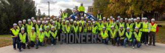 UW-Platteville construction management students in front of Pioneers sign on campus