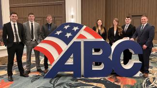 UW-Platteville student members of the ABC Construction Management Competition Team standing behind the ABC logo sign 