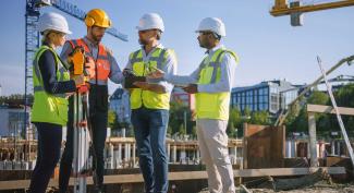 Four professional engineers at work on construction site