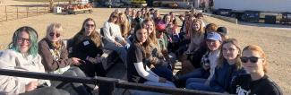 UW-Platteville students sitting in a wagon in front of a red barn