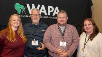 A group of four individuals posing in front of a black backdrop that reads WAPA