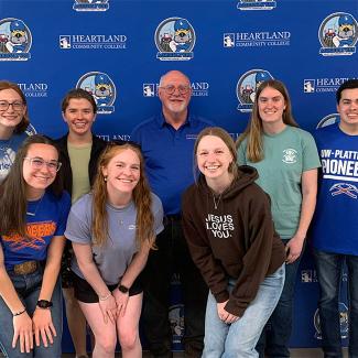 Group of individuals smiling and posing in front a blue backdrop.
